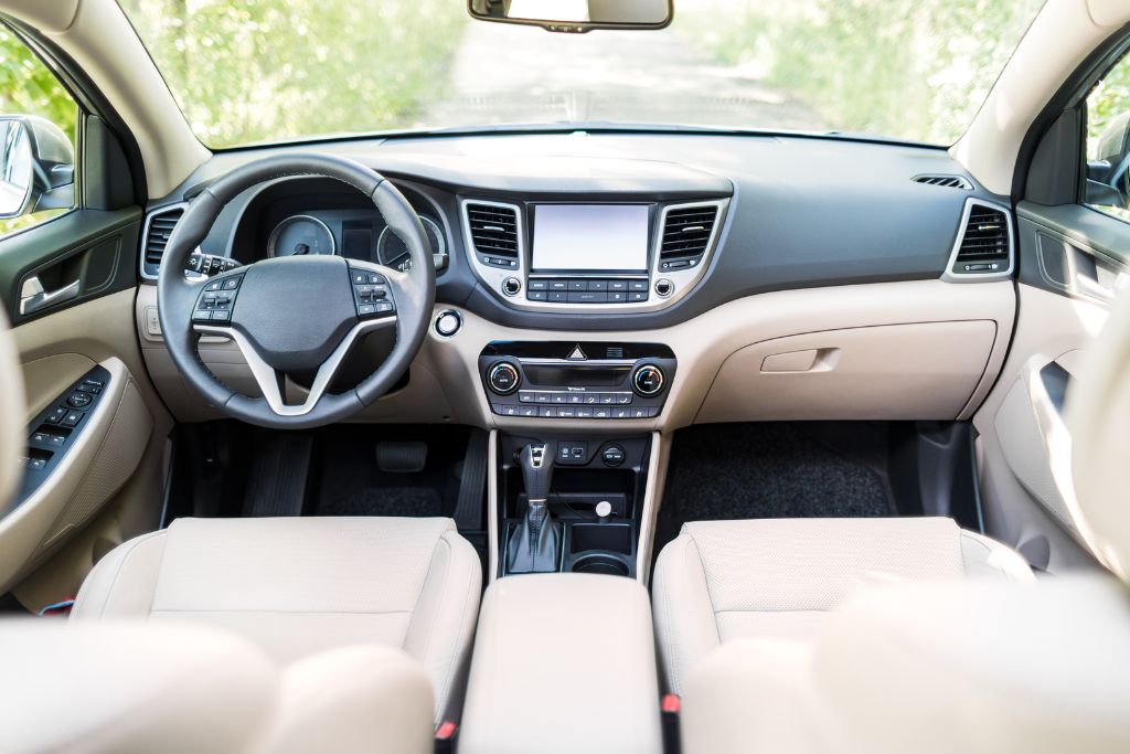 Interior view of a car with a well-maintained dashboard and seats, seen through the front windshield. The clean and preserved look highlights the role of window tinting in protecting interiors from UV damage.